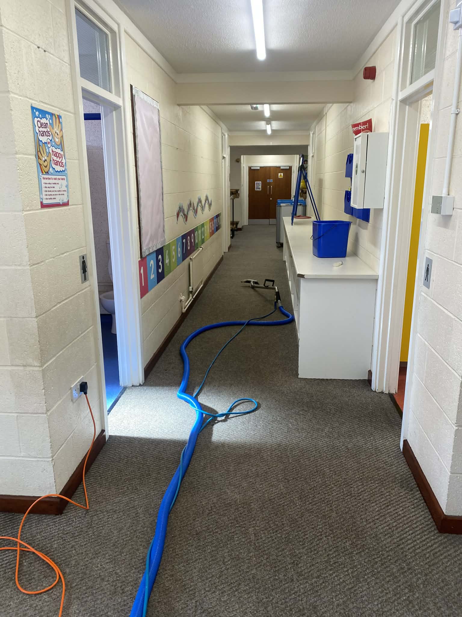 Hot water extraction wand cleaning patterned commercial carpet in venue