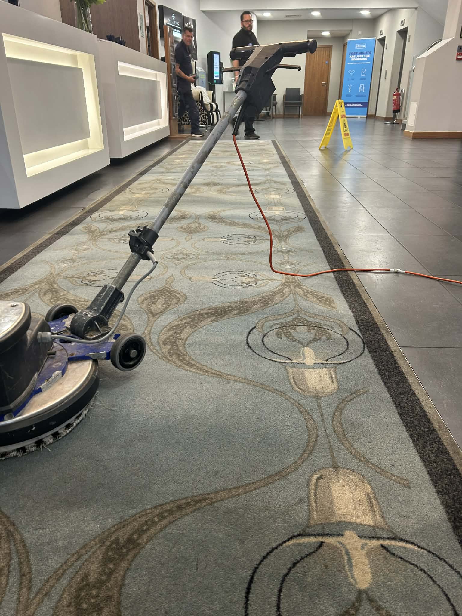 Captain Carpet Clean team cleaning ornate hotel reception carpet with rotary machine